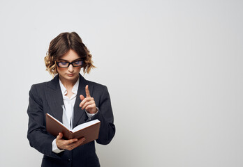 Business woman with a book in her hands on a light background classic suit fashionable hairstyle Copy Space