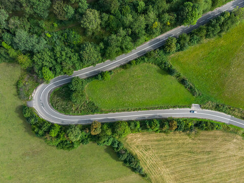 Aerial top down view to Hard curve on road near bushes and trees in mountains
