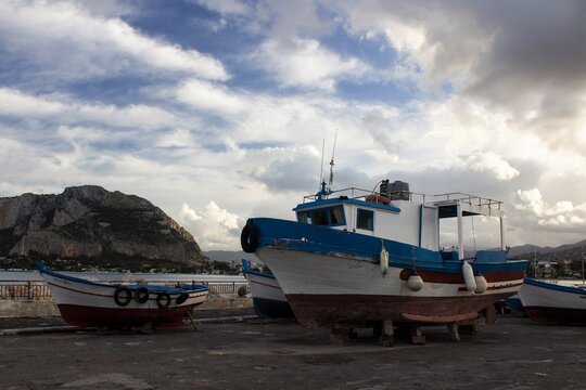 evocative image of dry fishing boats for maintenance with a mountain in the background and low clouds
