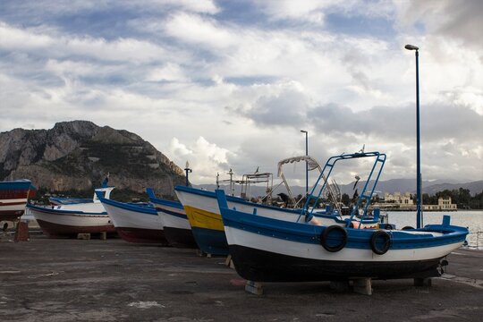 evocative image of dry fishing boats for maintenance with a mountain in the background and low clouds

