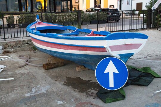 curious image of a dry fishing boat with a road sign leaning on the bow