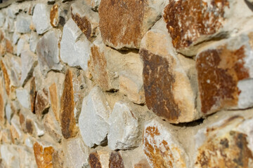 Background of flat stones and cement, decorative wall made of natural materials. Stony hard surface made of parts of different sizes and shapes with a sandy tint