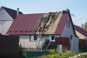 The roof of a house after a fire with torn off sheets of metal roofing and charred boards.