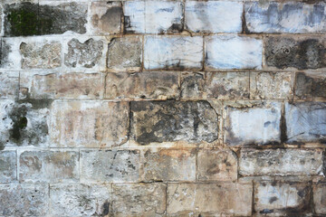 An old wall of gray blocks lined up in even rows. Texture.