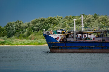 Navigable color barge floating on the river, carrying cargo in the Rostov region. Summer in nature on the don river and passing by, large and long ships made of painted metal