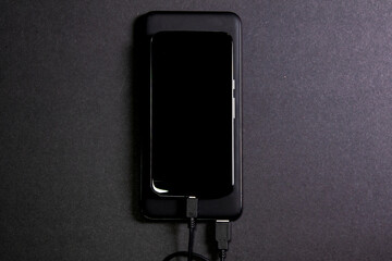 Smartphone connected to a power bank. Way to charge the battery of a mobile phone without...