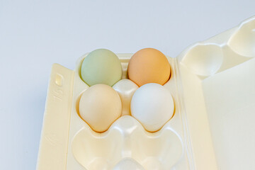 Fototapeta premium Multicolored chicken eggs lie in foam containers for storage and carrying on a light background. Close up. Soft focus