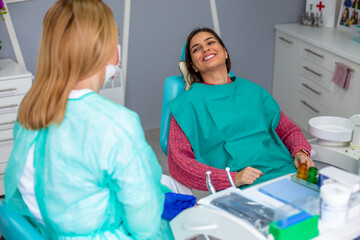 Female dentist in the dental office talking with female patient and preparing for treatment.