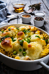Noodle casserole with cauliflower, minced meat, mozzarella cheese and cream sauce on wooden table
