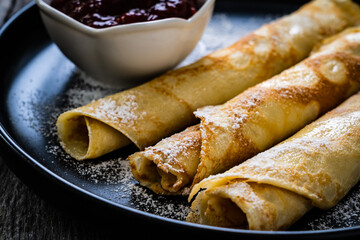 Sweet crepes with strawberries  jam on wooden table
