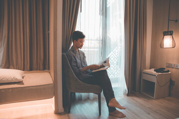 Vintage portrait of a male reading in a room by the window.