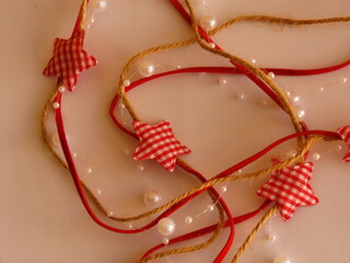 Beautiful garland with red stars made of fabric and beads for decorating a Christmas tree on a white background close-up. Happy New Year.