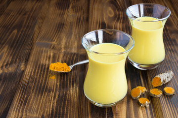 Closeup of gold milk with turmeric in the glasses on the wooden background