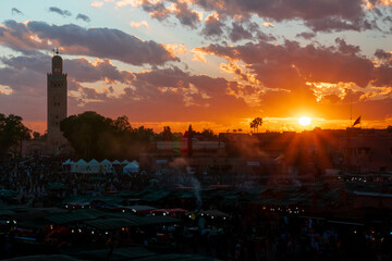 Yamaa el Fna Square with its markets and crowds of people and the tower of the mosque in the...