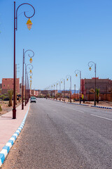 Wide angle shot of buildings, street lamps and road of the town of Tagonite in Draa Valley, Morocco