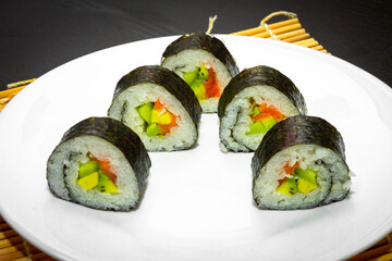 Delicious fresh sushi close-up on a white plate and a black table. Japanese cuisine.
