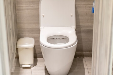 A white toilet bowl with plastic bin in dirty toilet