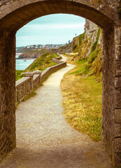 Obraz premium walking path, trail through arched stone door on a beach