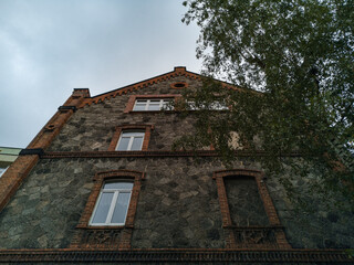Fototapeta premium Upward view to old house made by stone and brick with window frame without window