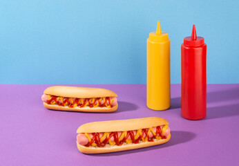 Two hotdogs and squeeze bottles of liquid mustard and ketchup