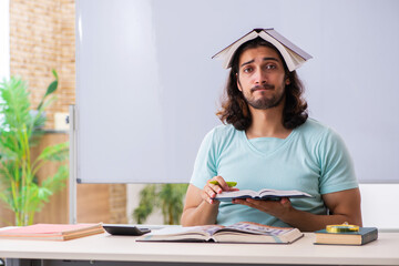 Young male student preparing for exams in the classroom