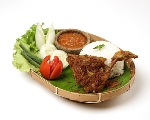 Fried chicken with ripe golden skin laid out on a wooden sheet on a white background, plus white rice, chili sauce and various vegetables, view from above. commonly used for menus and picture packs.