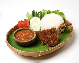 Fried chicken with ripe golden skin laid out on a wooden sheet on a white background, plus white rice, chili sauce and various vegetables, view from above. commonly used for menus and picture packs.