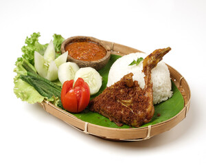 Fried chicken with ripe golden skin laid out on a wooden sheet on a white background, plus white rice, chili sauce and various vegetables, view from above. commonly used for menus and picture packs.