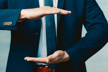 Hands of a man in a blue jacket folded in the shape of a sphere or as if pulling something.