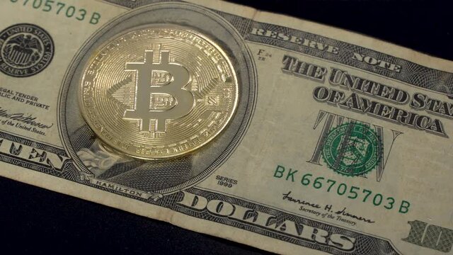 The bitcoin coin lies on a $ 10 bill in close-up. Money and Finance.
