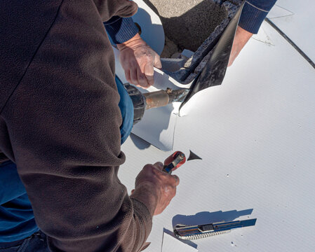 Worker applies pvc membrane roller on roof very carefully. Correct welding with hand-welder, corner.