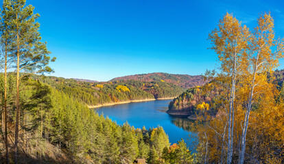 Obraz premium Colorful autumn landscape with mountain lake in pine forest. Berovo lake, North Macedonia.