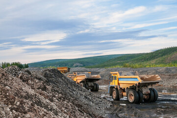     Dump truck and wheel loader in operation. Mining.
  A wheel loader loads mountain soil into the body of a dump truck.
