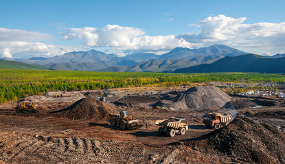     Dump truck and wheel loader in operation. Mining.   A wheel loader loads mountain soil into the body of a dump truck.  © Letopisec