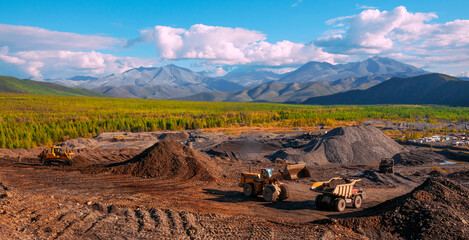     Dump truck and wheel loader in operation. Mining.   A wheel loader loads mountain soil into the body of a dump truck.  © Letopisec