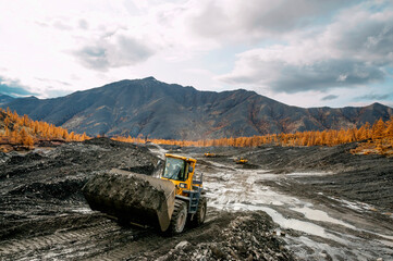 Wheel loader at work. It transports gold-bearing mountain soil to the hopper of the washing device. The gold mining industry in Eastern Siberia widely uses such equipment as front loader, bulldozer, 