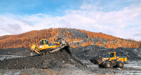 Bulldozers and wheel loaders at work. Mining.
Bulldozers cut the topsoil in mountainous forested areas and wheel loaders transport the soil