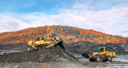Bulldozers and wheel loaders at work. Mining. Bulldozers cut the topsoil in mountainous forested areas and wheel loaders transport the soil © Letopisec
