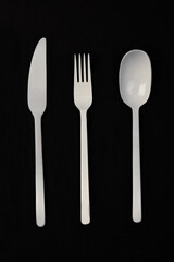 white painted metal cutlery on black background