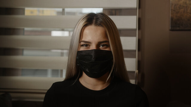 Charming young beautiful blonde woman at work taking off her black mask , pandemic and office working concept