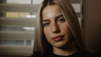 Young blonde charming attractive pretty blonde hair woman looking at camera in office or at home, dressed in blond black