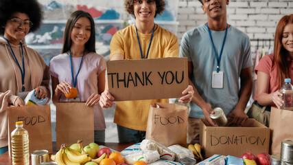Cropped shot of group of diverse young volunteers packing food and drinks donation, Guy holding...