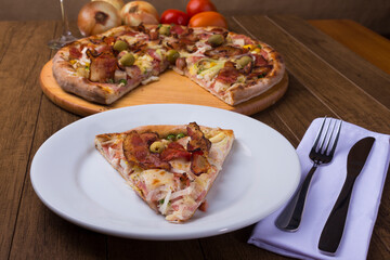 Portuguese Pizza slice made with ham, pea egg, heart of palm, pepperoni, onion and mozzarella and bacon. Served on the plate with sliced ​​pizza in the background.