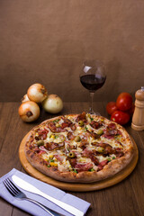 Photograph of Portuguese Pizza made with ham, pea egg, heart of palm, pepperoni, onion and mozzarella and bacon. Glass of wine, onions and rustic tomatoes. Photo of typical Brazilian food.
