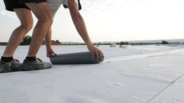 Worker folding synthetic pvc membrane on a flat roof