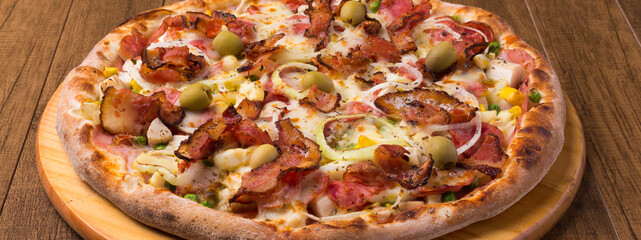 Complete Portuguese Pizza accompanied by a glass of red wine. Panoramic photography.