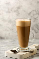 Coffee drink with whipped milk in tall glass cup with cinnamon.