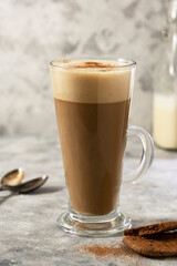 Coffee drink with whipped milk in tall glass cup with cinnamon.
