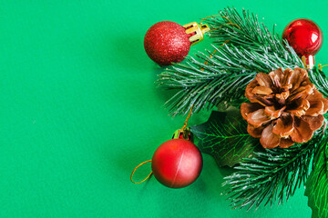 Christmas decoration of holly berries and cones with red balls on a green background. New Year and Christmas concept