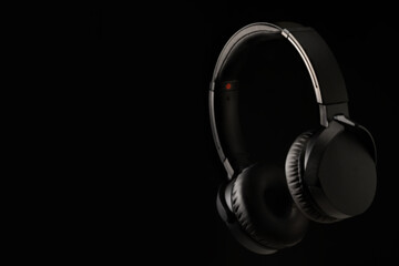Fototapeta na wymiar black headphones on black background with side lighting